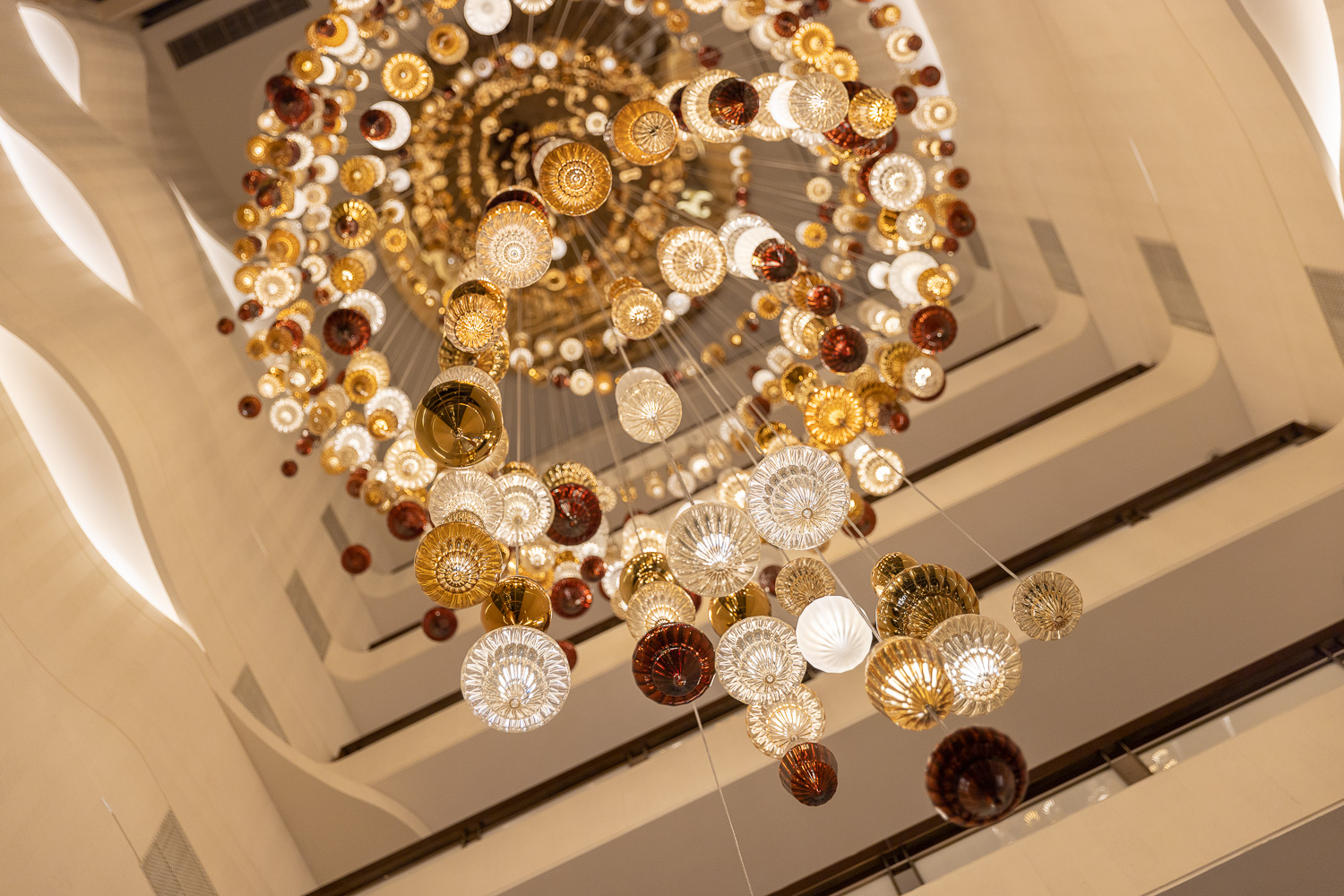 BUTTONWOOD glass disc chandelier by SHUCHUANG, seen down the stair void
