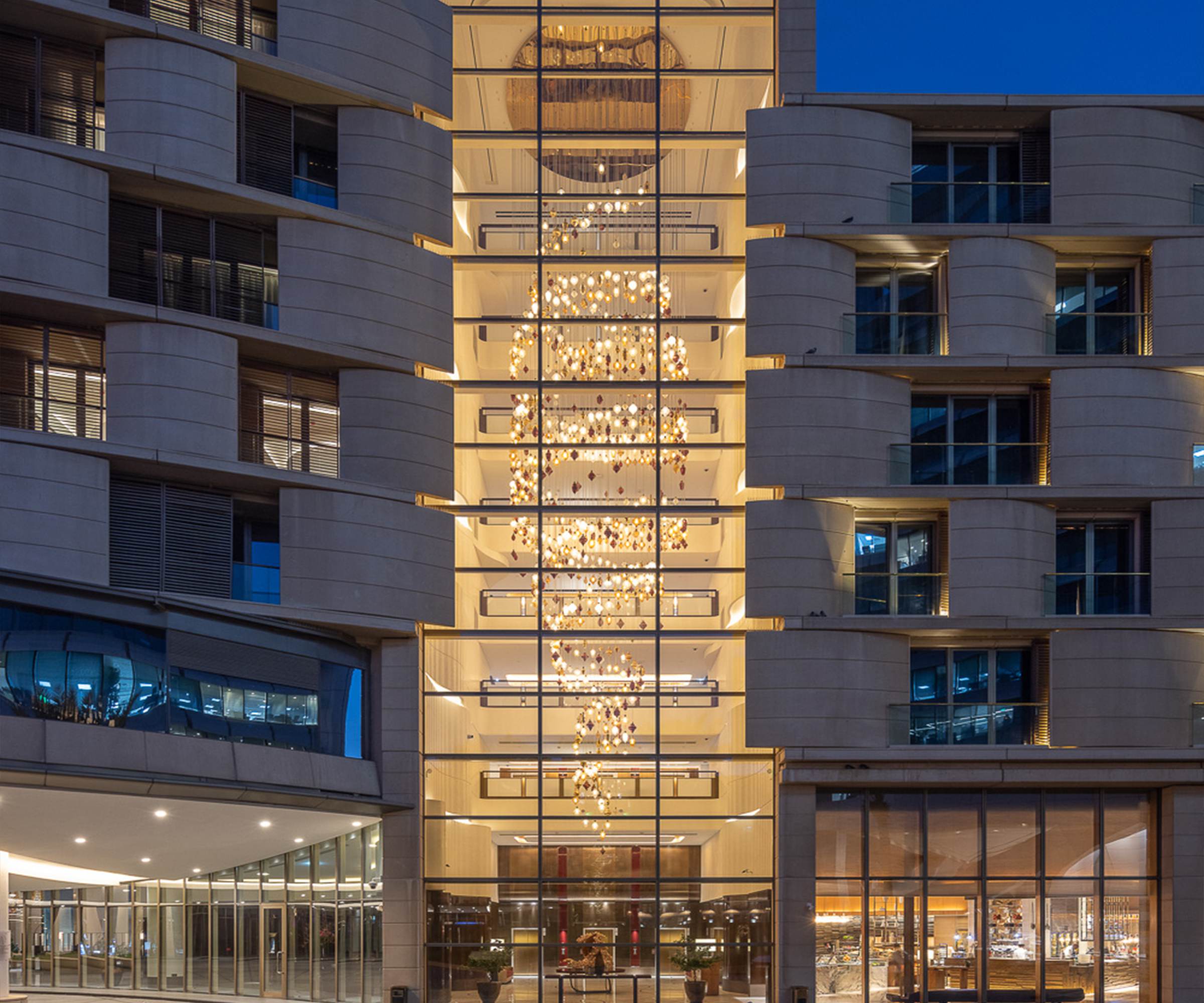BUTTONWOOD chandelier seen through the building glazing at night