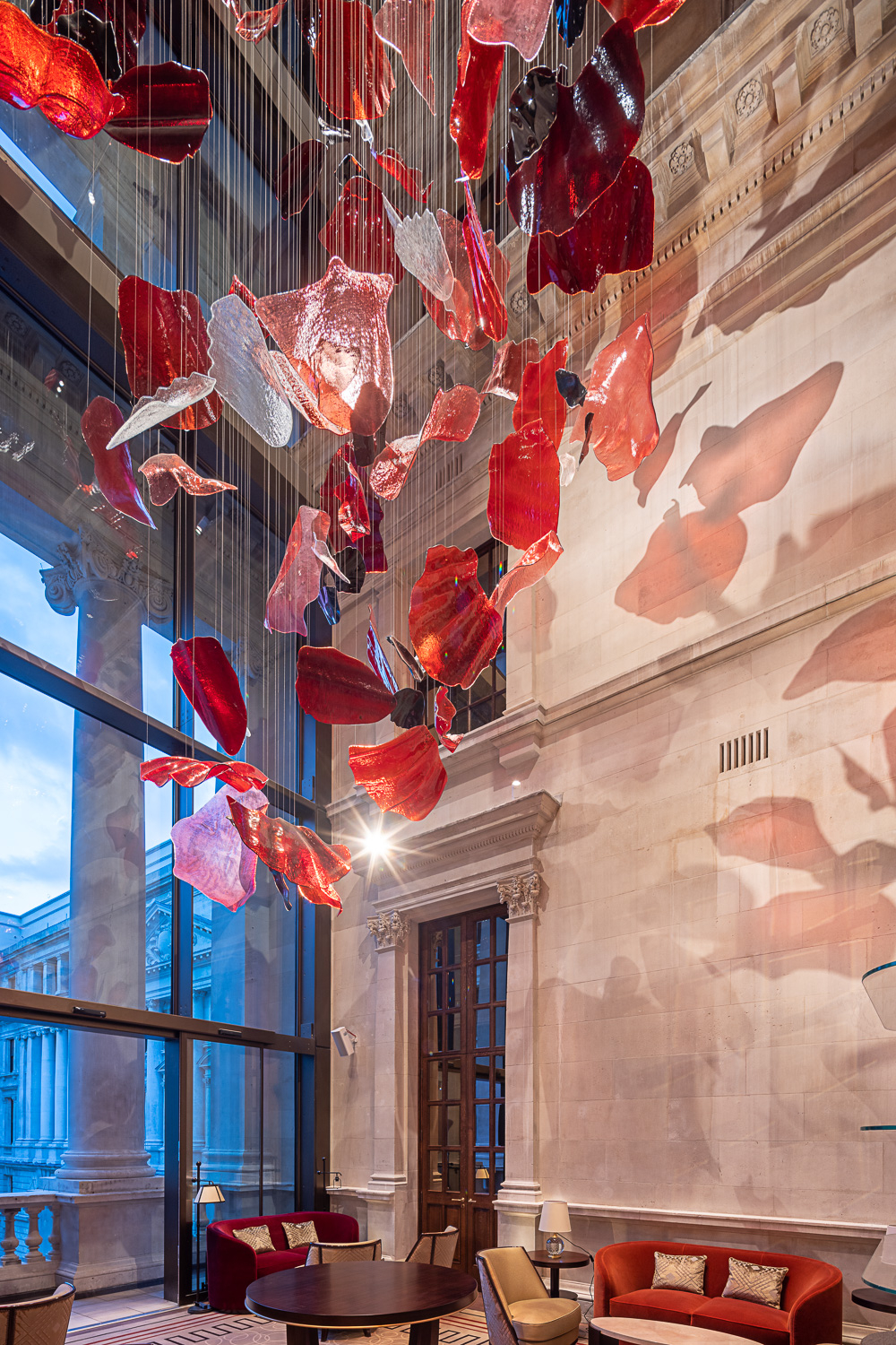 ROSSO red glass forms high in the pale stone hall