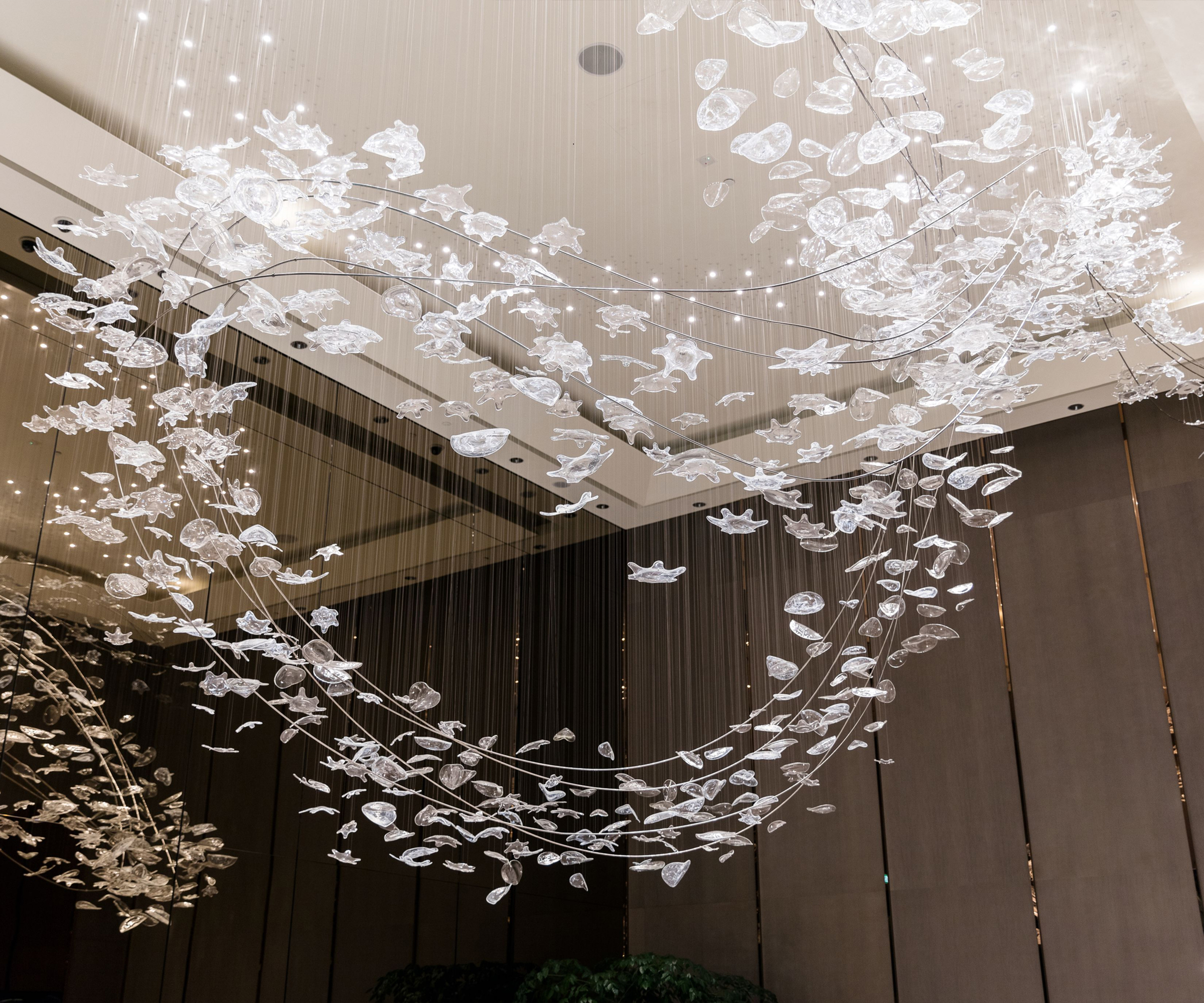 STELLAR metallic glass leaf chandelier by SHUCHUANG, curve seen across the lobby
