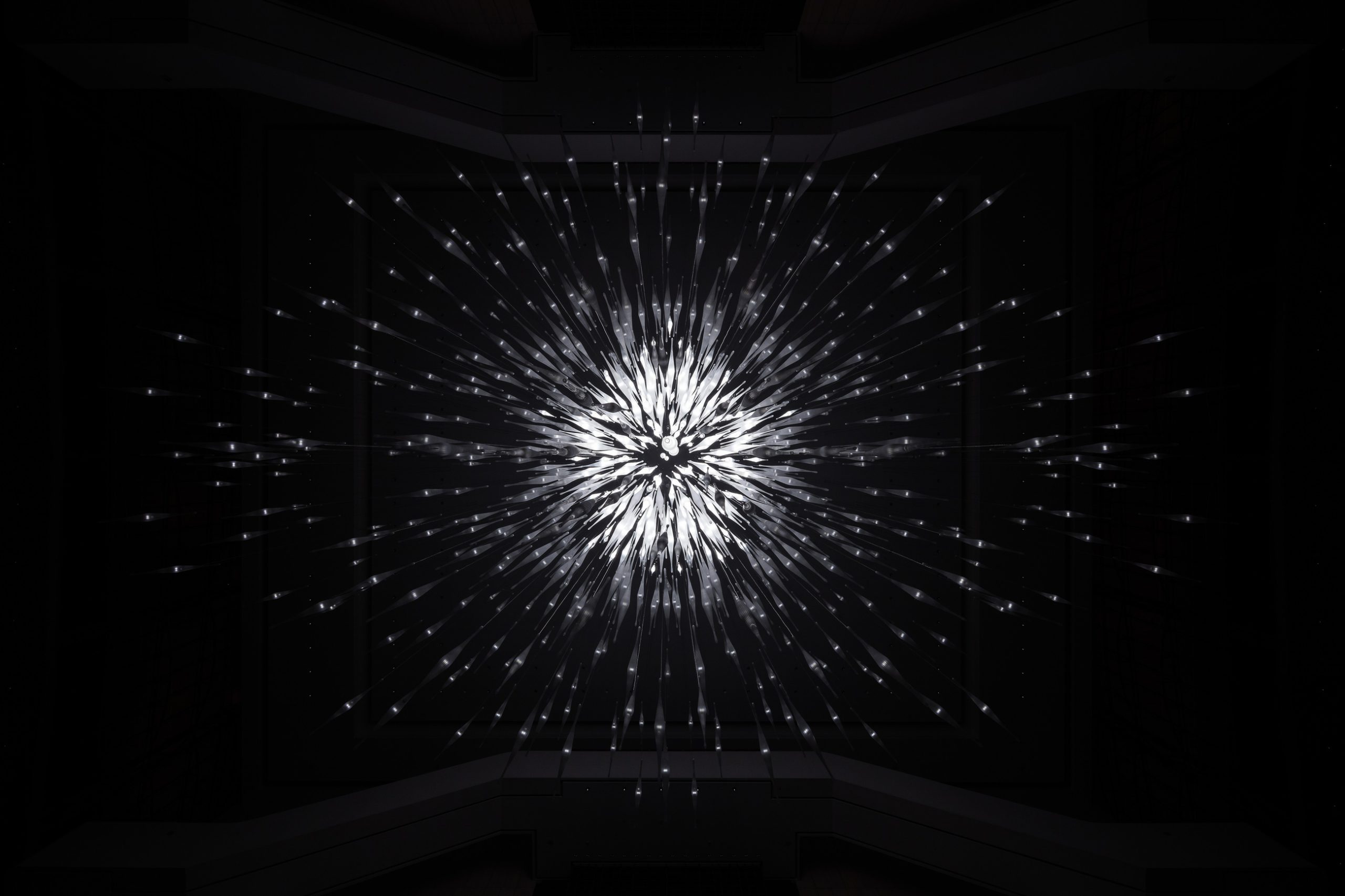 STARBURST chandelier seen from the atrium floor against the window wall