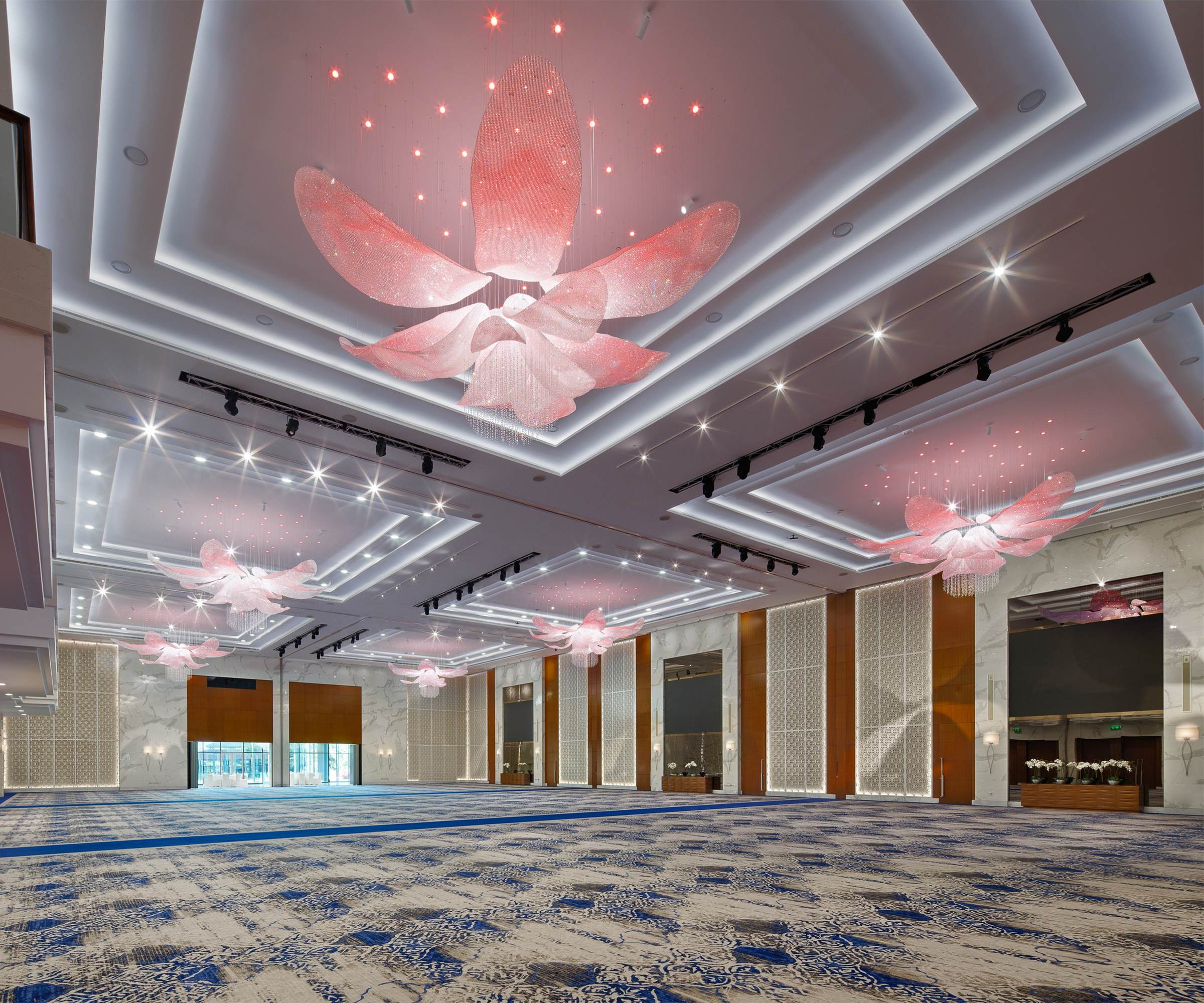 FLEUR ceiling light lit in red above a hotel ballroom