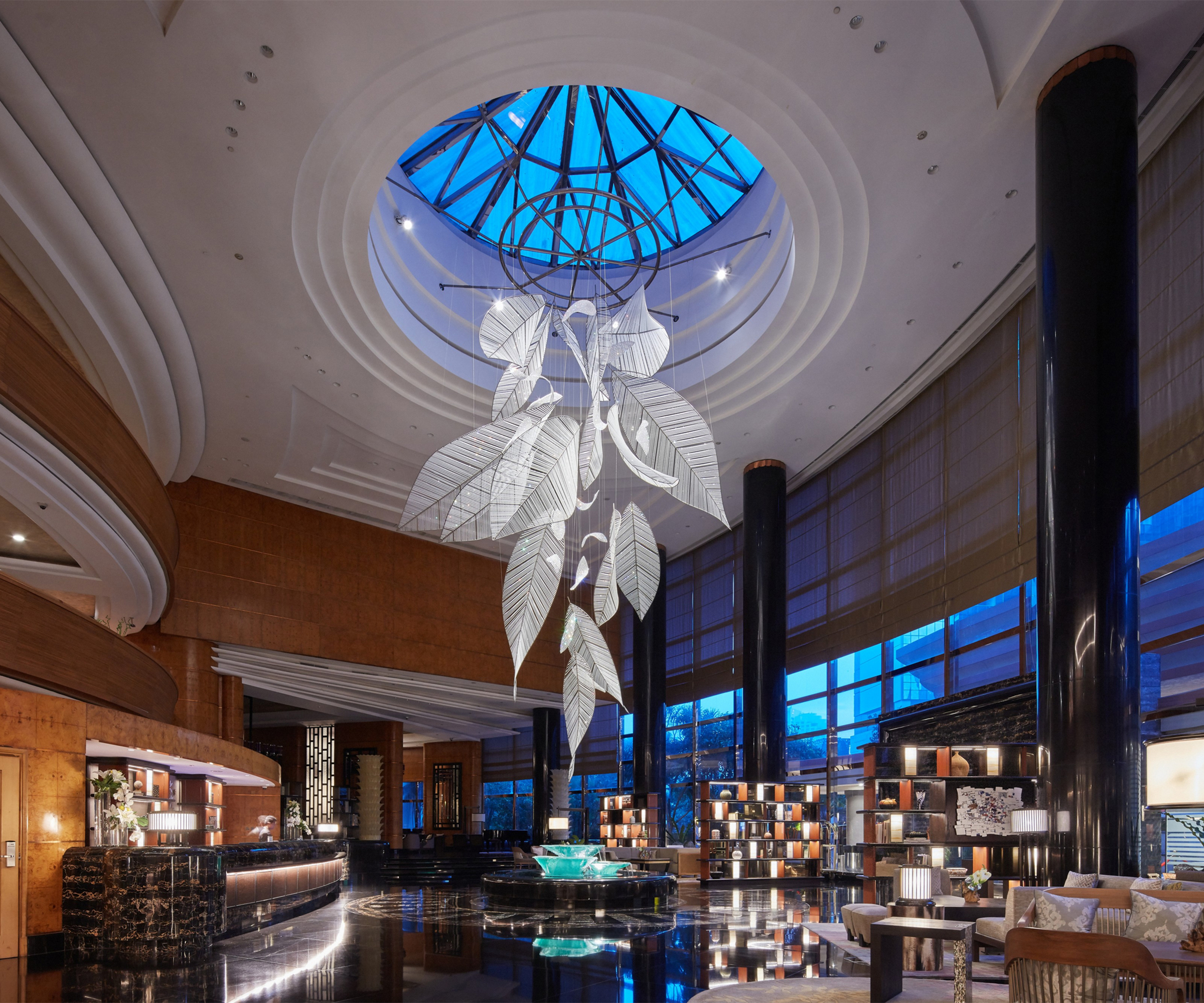 FOLIA leaf cluster hanging beneath a round skylight in a hotel lobby