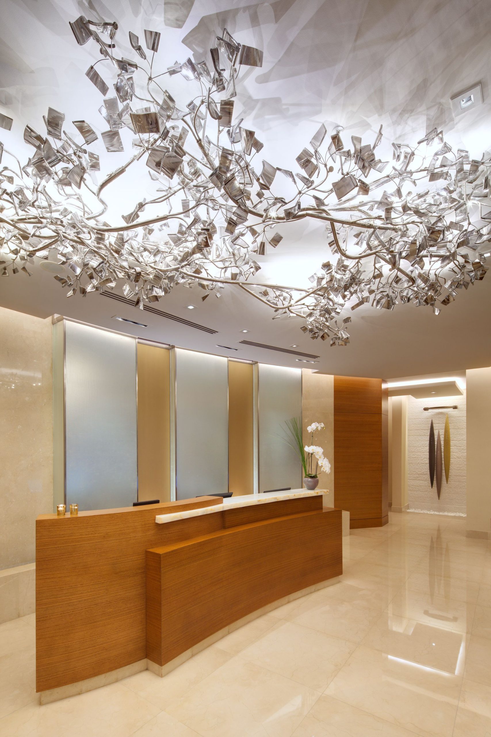 FROST custom lighting above a reception counter, glass leaves on polished arms