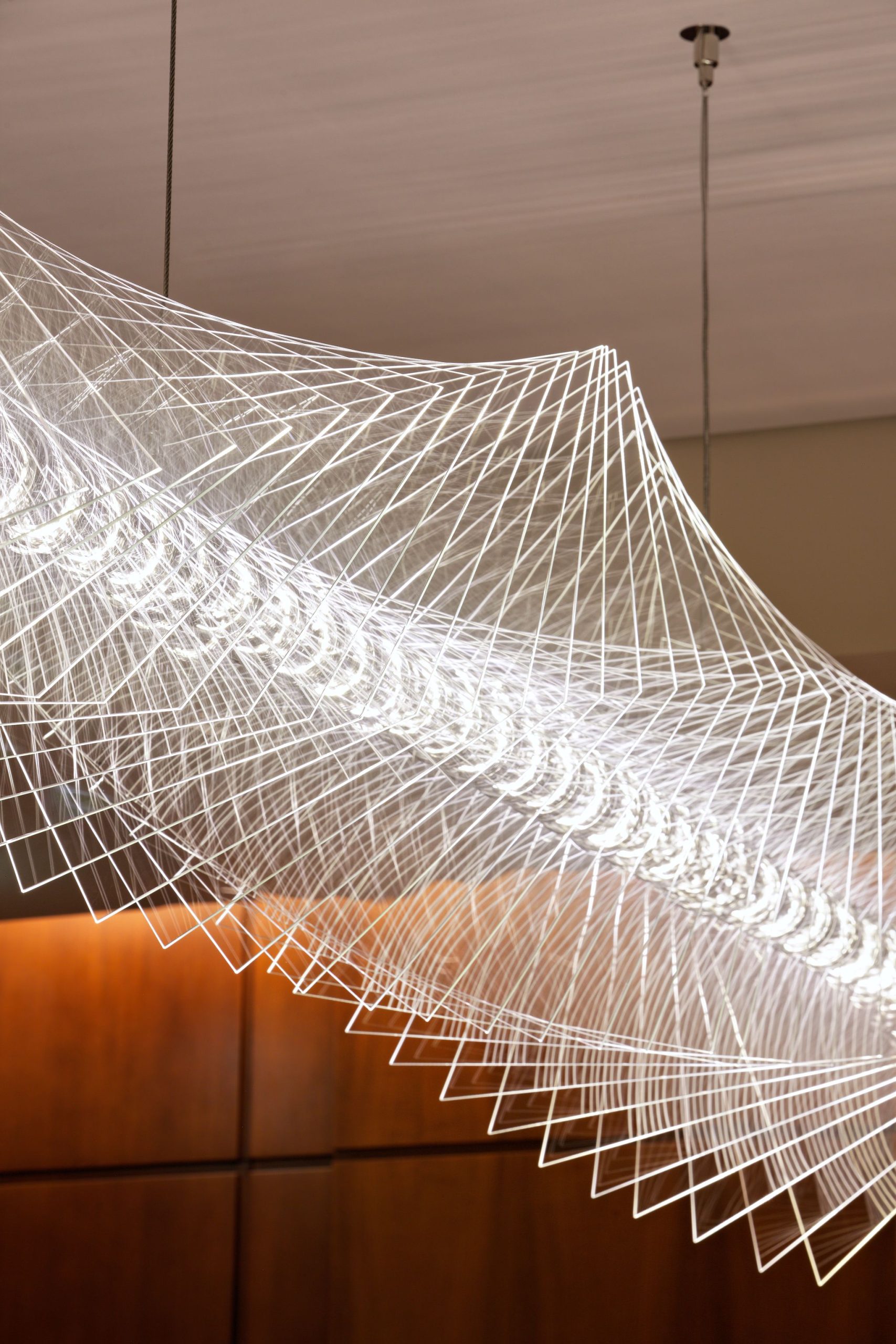 WEBB chandelier, wave profile of the edge-lit fins against a timber wall