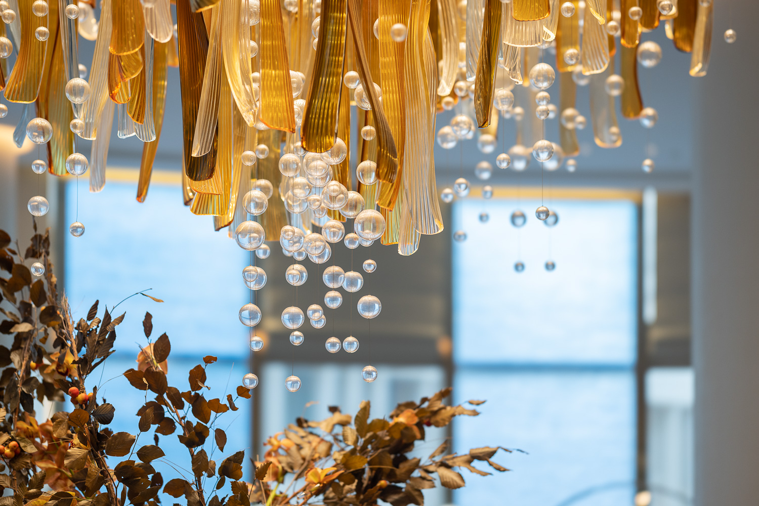 AURELIA amber glass chandelier by SHUCHUANG, blades and sphere strings against the window